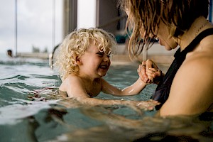 This image shows a small child swimming with mother by James Bowden, UK lifestyle photography, represented by Horton-Stephens photographer’s agents specialises in natural and authentic  lifestyle outdoors nature photographic images.