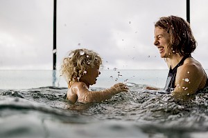 This image shows a small child swimming with mum by James Bowden, UK lifestyle photography, represented by Horton-Stephens photographer’s agents specialises in natural and authentic  lifestyle outdoors nature photographic images.