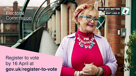 woman in pink jumper smiles with necklace made of letters which reads I'm registered to vote campaign by The Electoral Commission shot by portrait photographer Nick Dolding represented by photo agency Horton Stephens photography